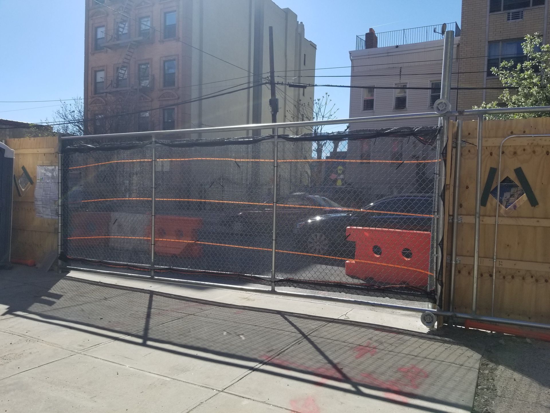 A tall building under construction, orange safety netting encloses the exposed metal beams.