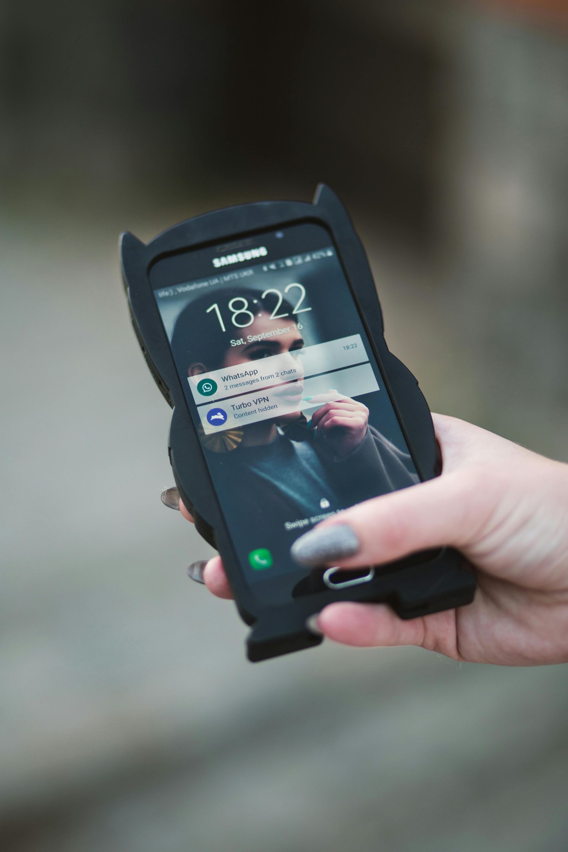 A person is holding a cell phone in a cat case.