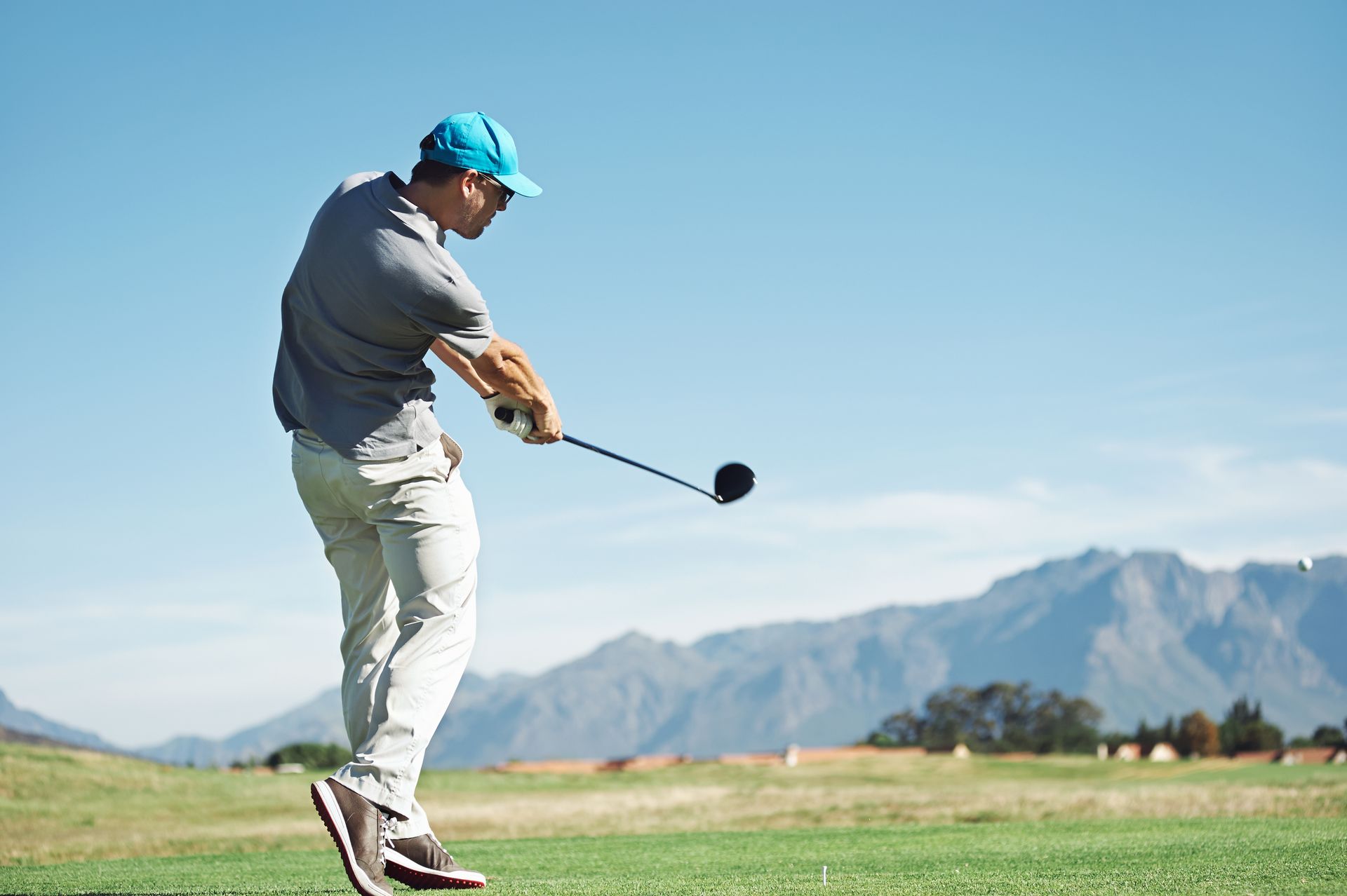 A man is swinging a golf club on a golf course.