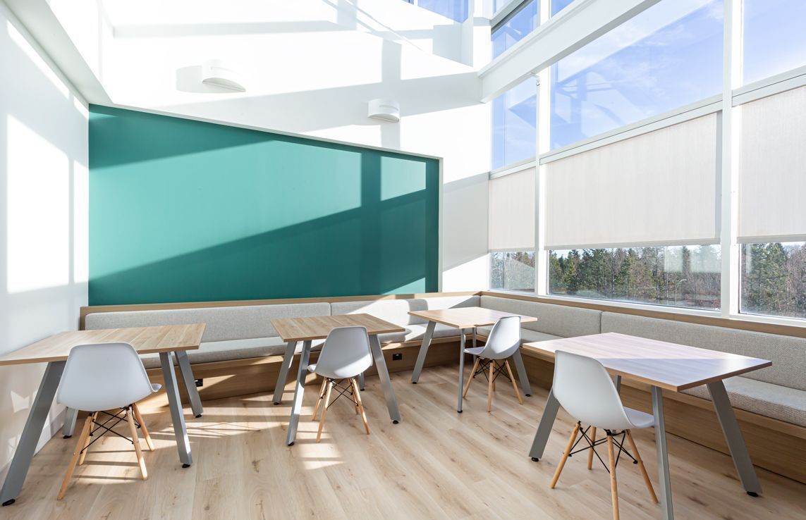 A room with tables and chairs in front of a large window.