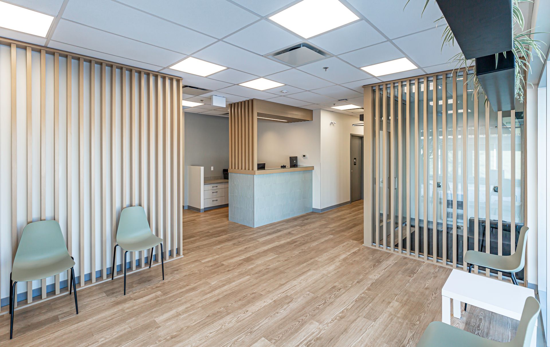 A waiting room with wooden floors , chairs and a counter.