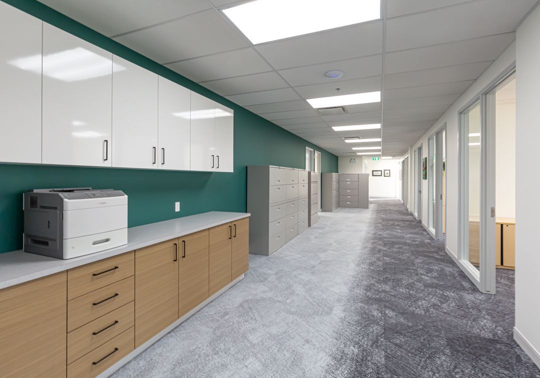A long hallway in an office building with a printer on the counter.