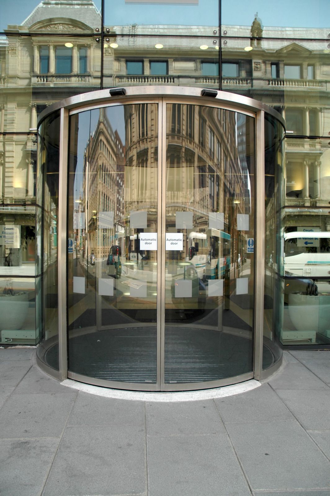 Revolving glass door entrance, reflecting a city street.