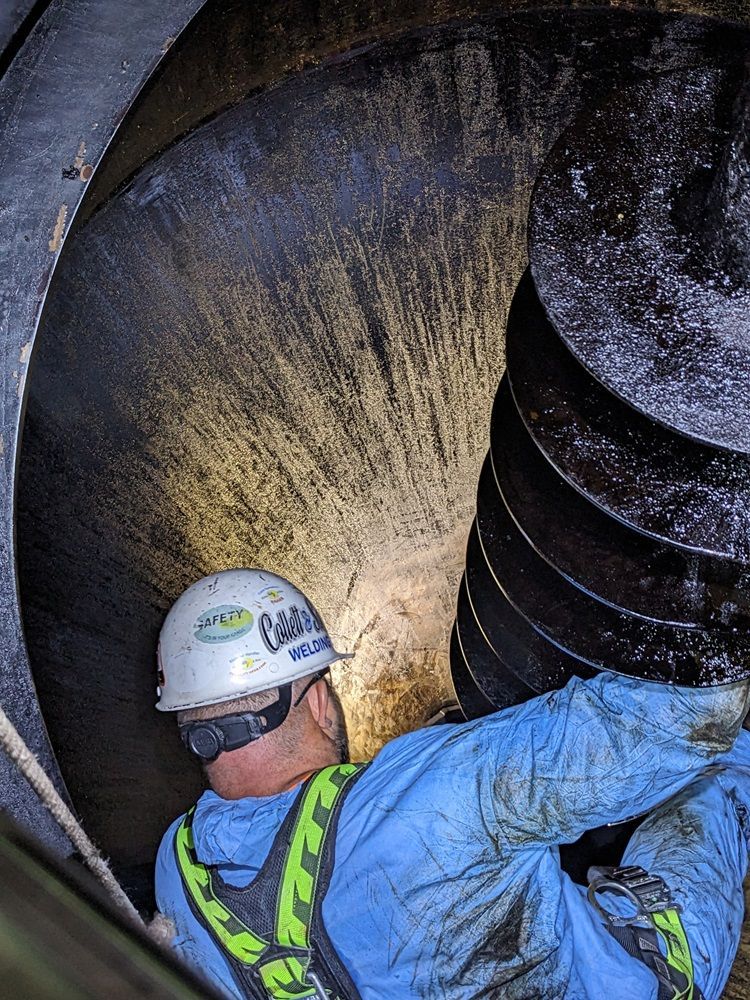 A man wearing a hard hat is working on a machine.