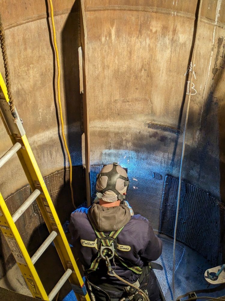 A man wearing a gas mask is sitting in a tank with a ladder.