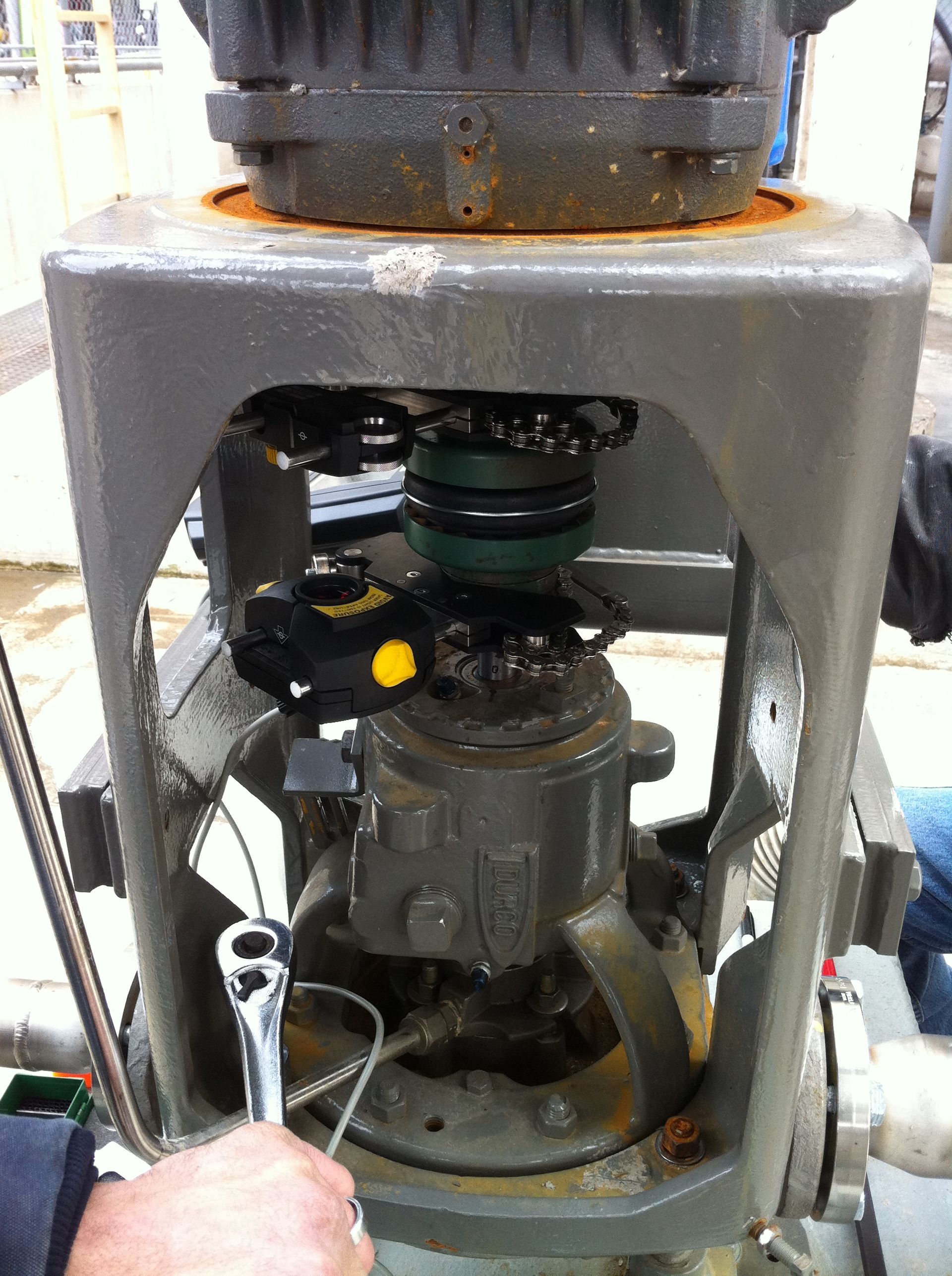 A person is working on a machine with a wrench