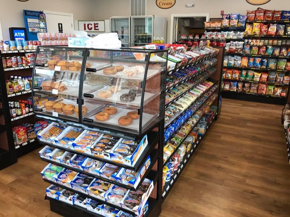 Inside a convenience store with snacks, pastries, and a cooler.