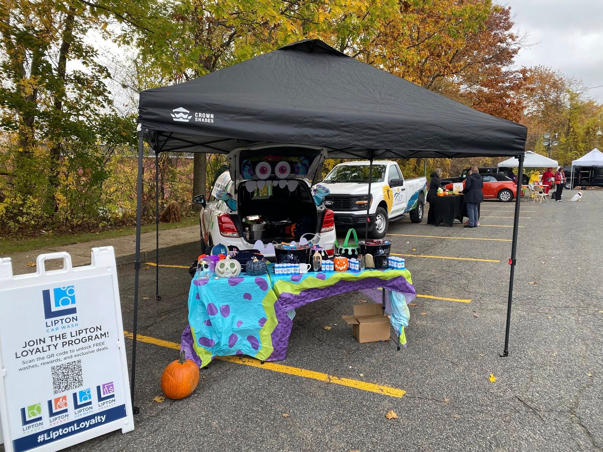 Booth with table displaying items, decorated with a Halloween theme, under a black canopy.