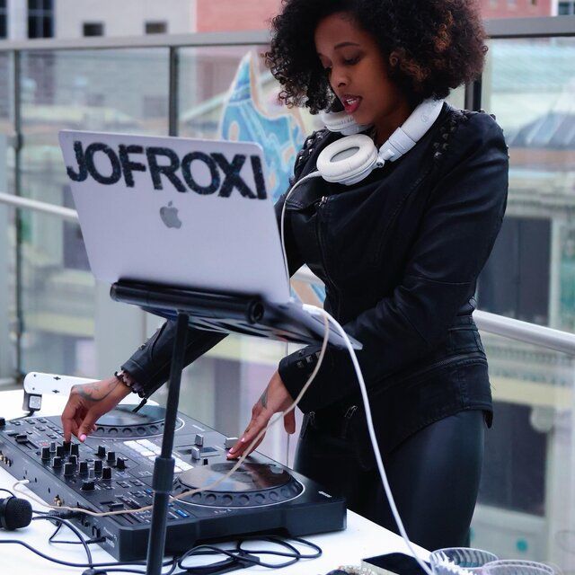 DJ mixing at an outdoor event with a laptop and turntable controller