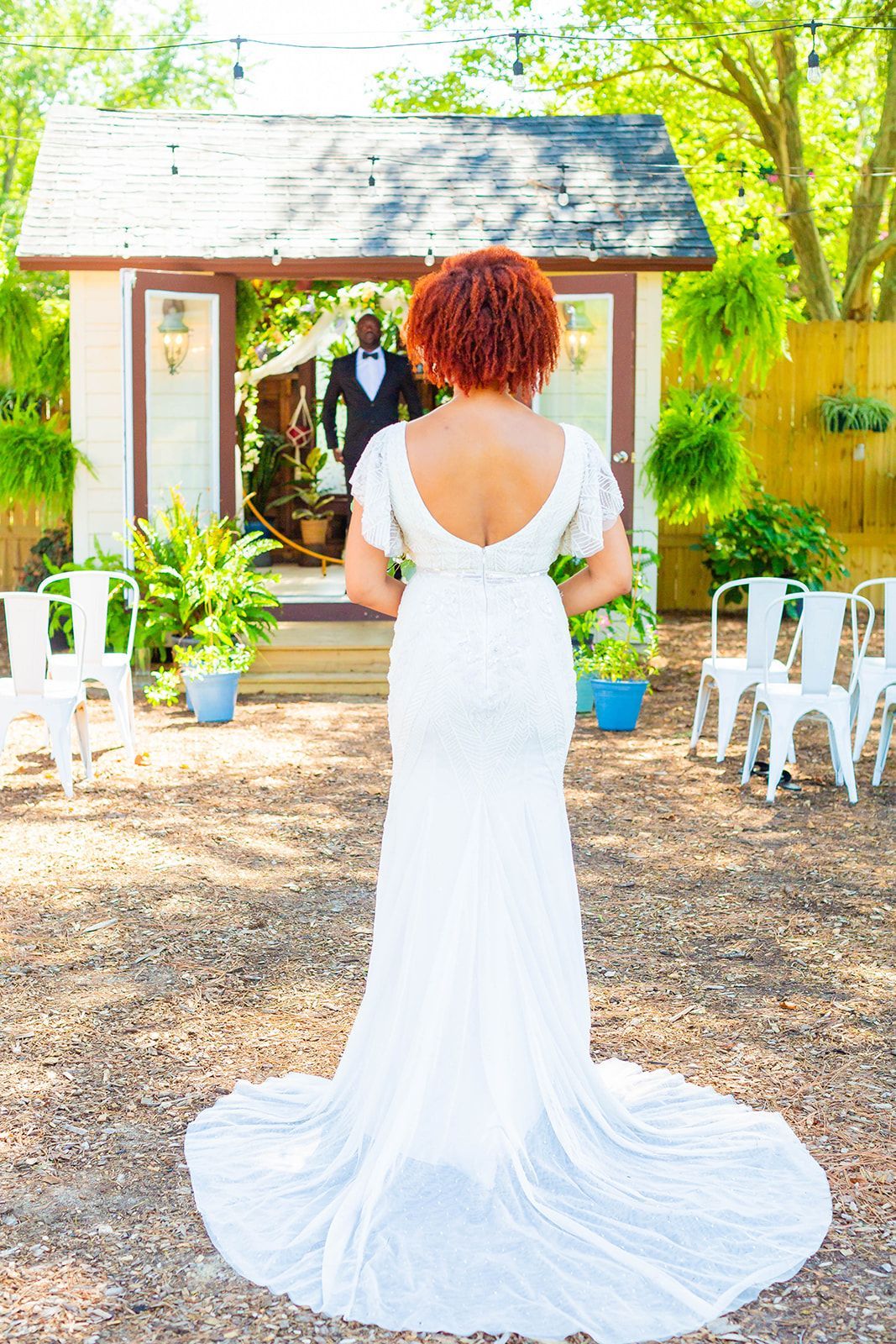 a bride in a white dress is standing in front of a man in a tuxedo .