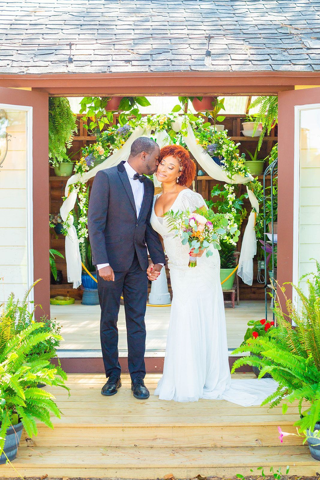 A bride and groom are standing in front of a building holding hands.