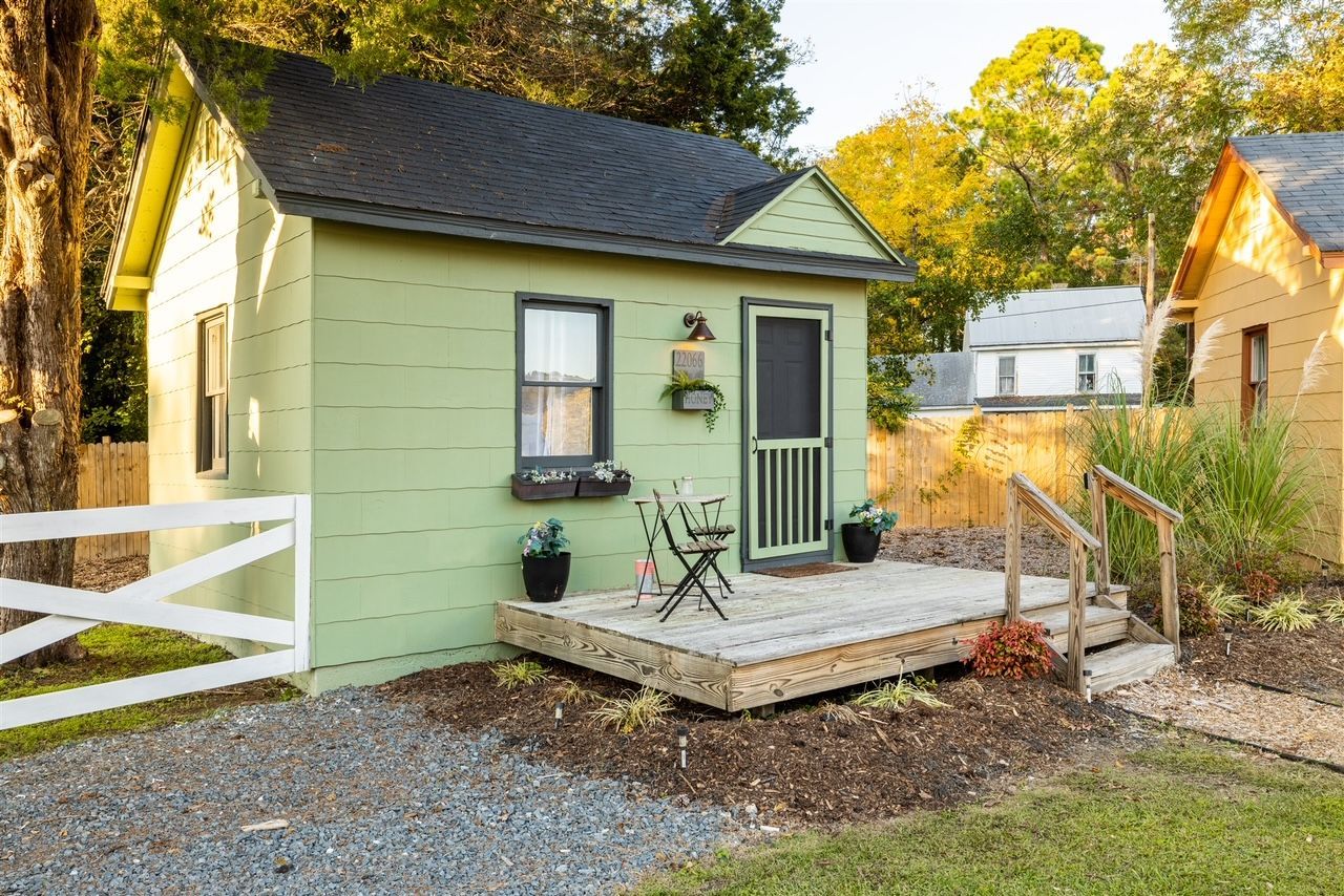 a small green house with a deck in front of it .