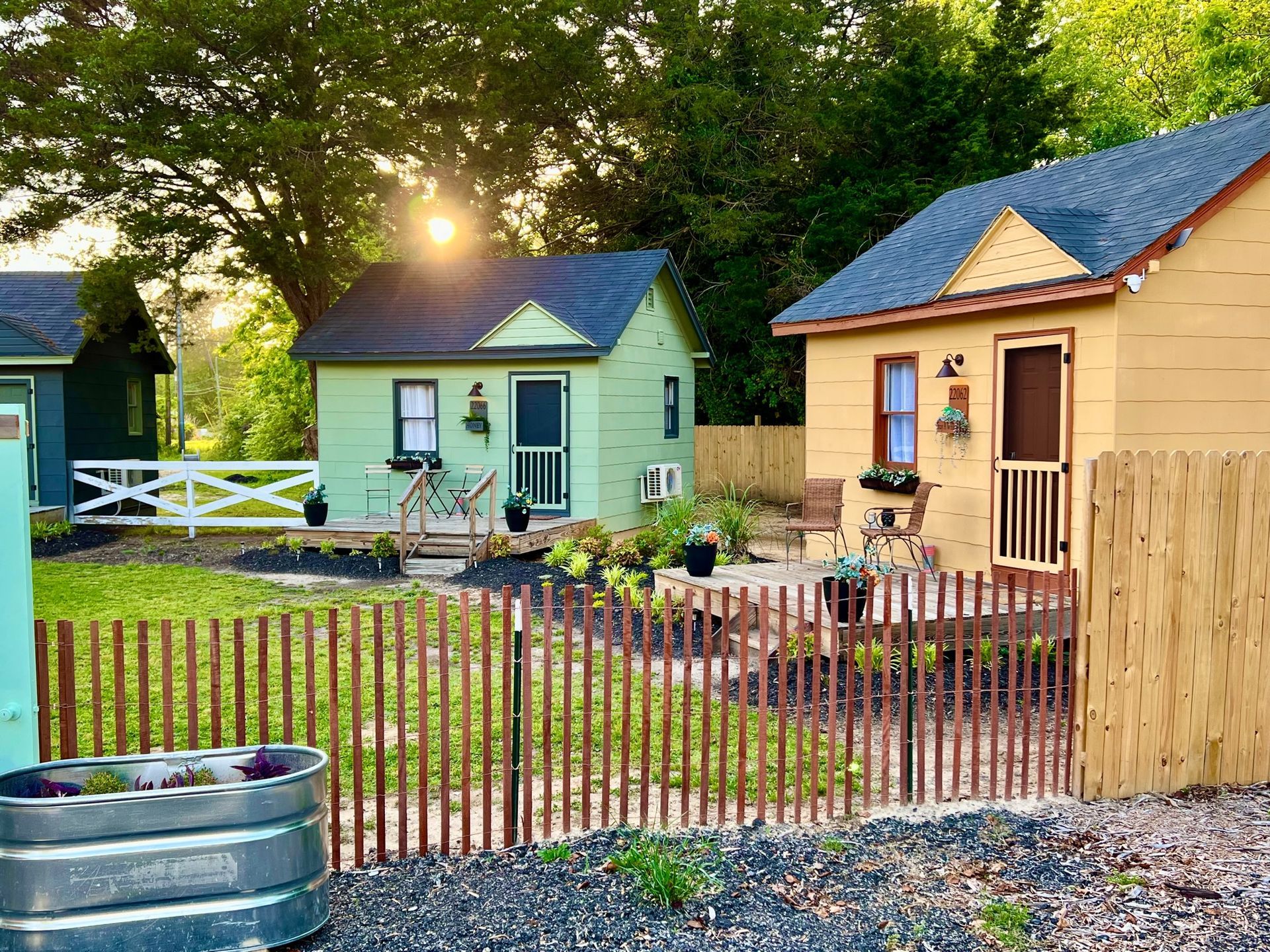two small houses are behind a wooden fence in a yard .