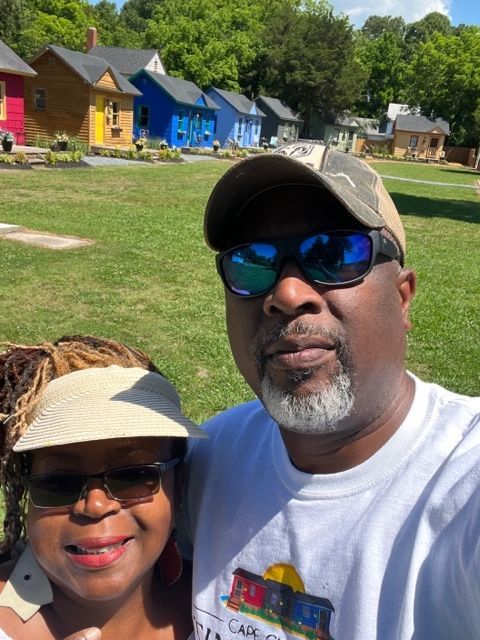 a man and a woman are posing for a picture in front of a field of houses .