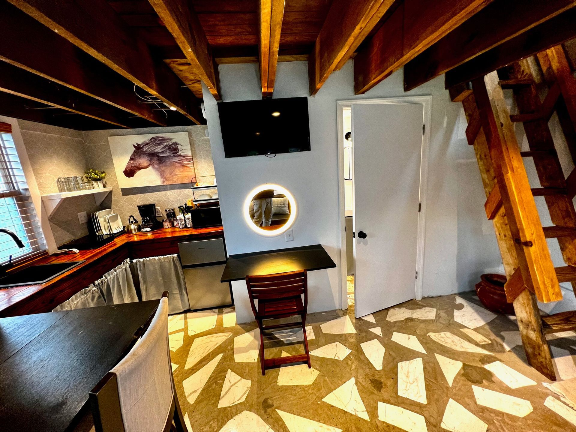 a kitchen with a table and chairs and a staircase leading up to the second floor .