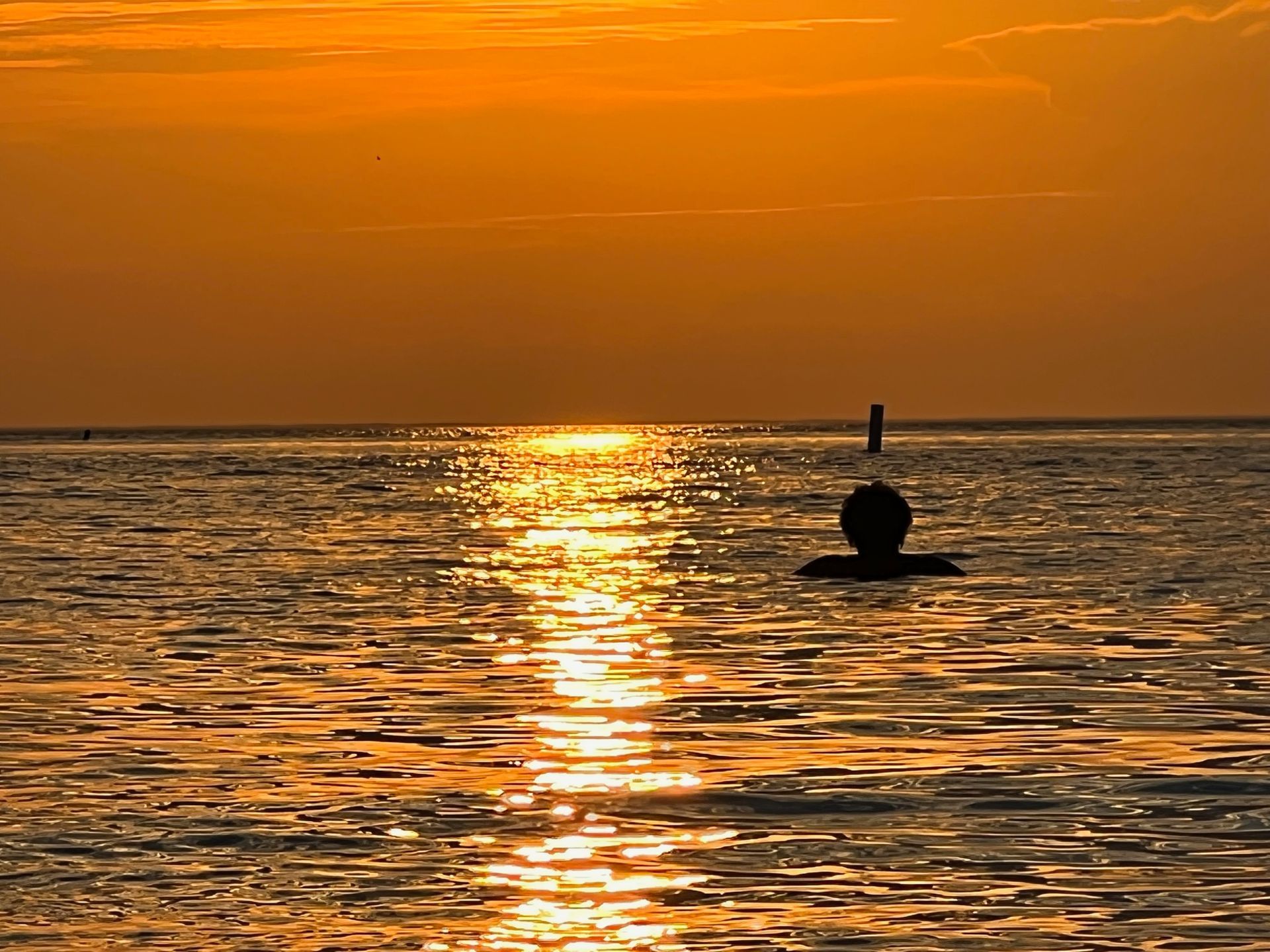 a buoy in the middle of the ocean at sunset .