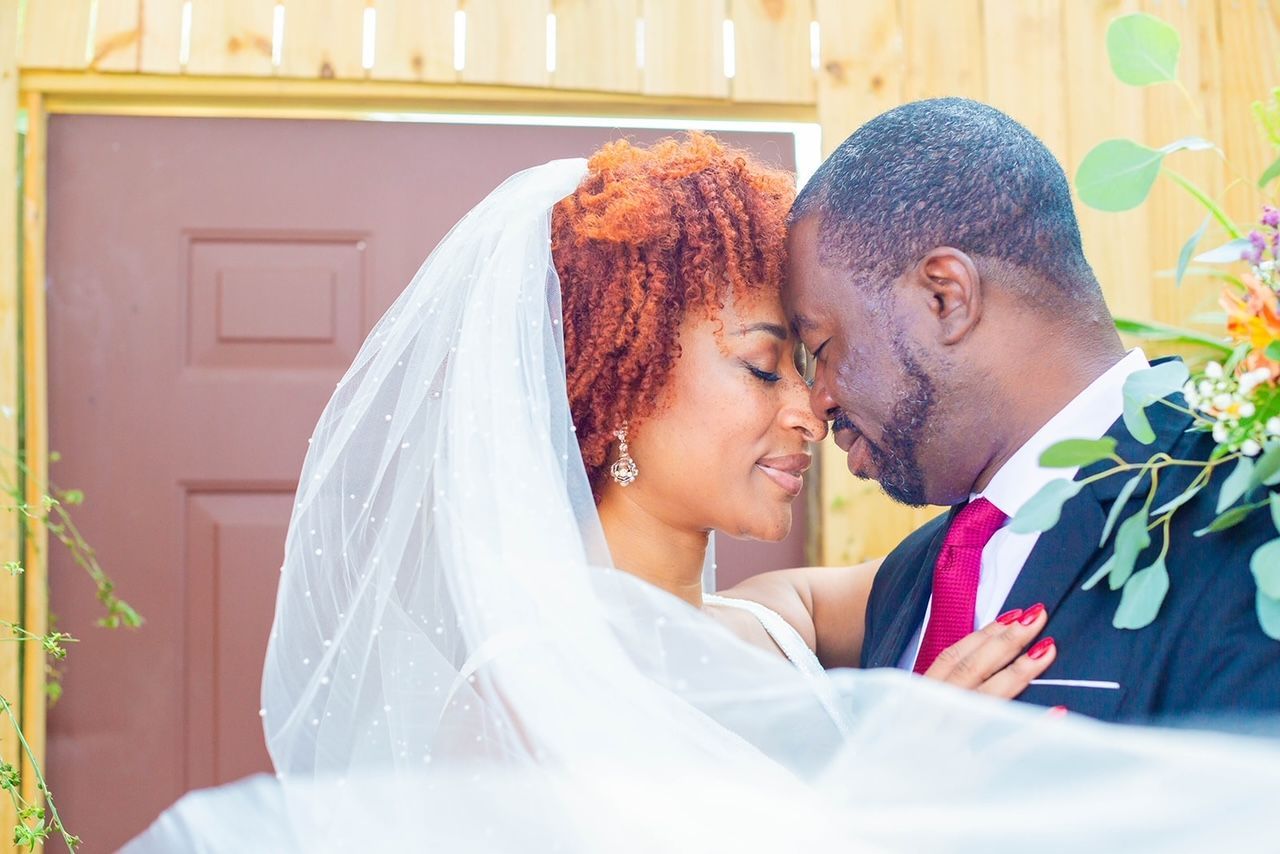 a bride and groom are standing next to each other in front of a door .