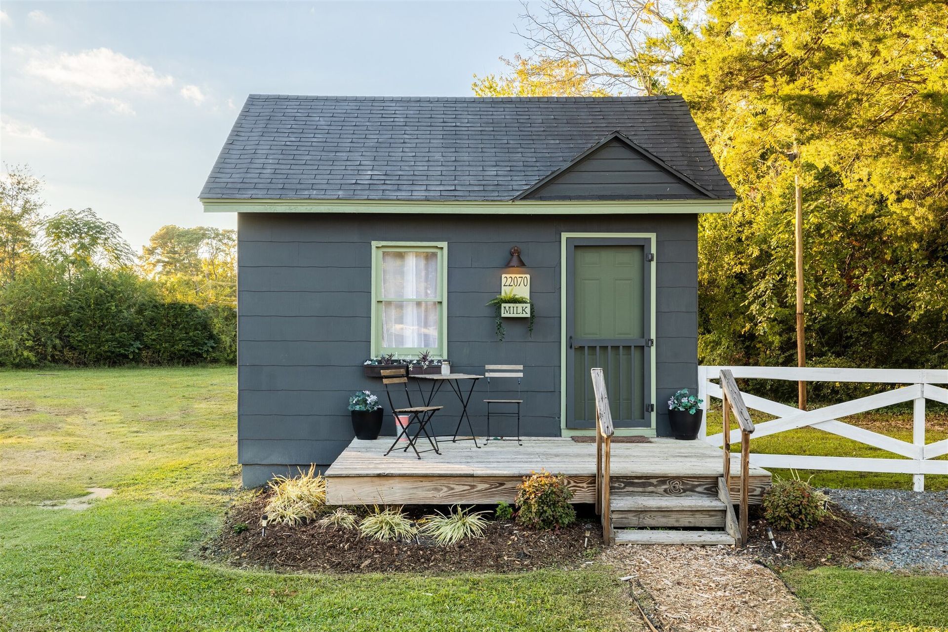 a small house with a porch and stairs is sitting in the middle of a grassy field .