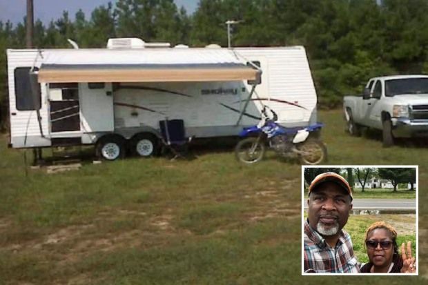 a man and woman are posing for a picture in front of a trailer
