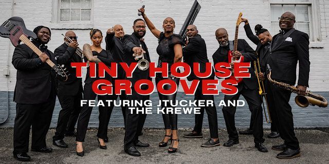Band in black suits posing outdoors with text: “Tiny House Grooves featuring Truck and the Krew.”