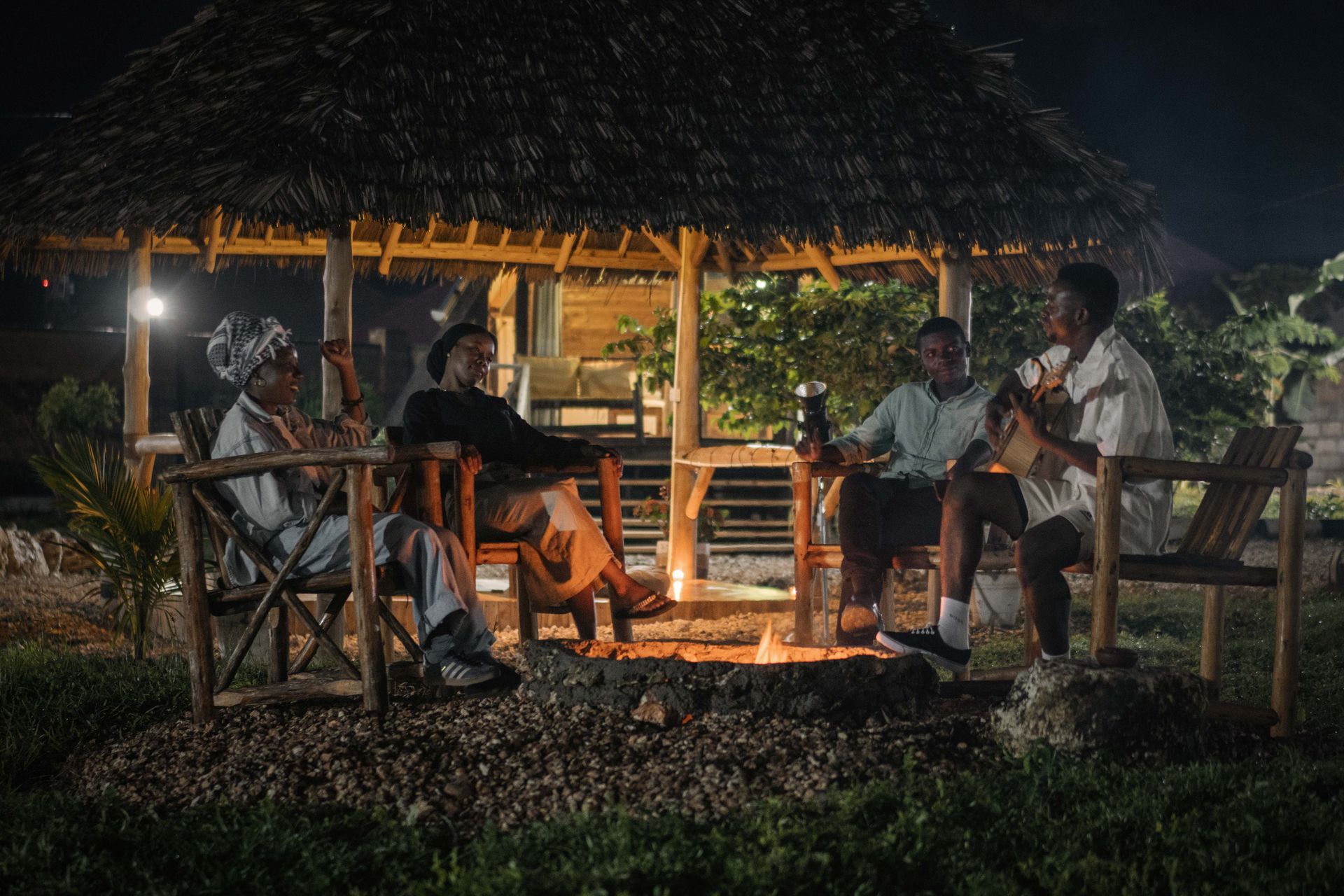 A group of friends sitting around a fire pit at night
