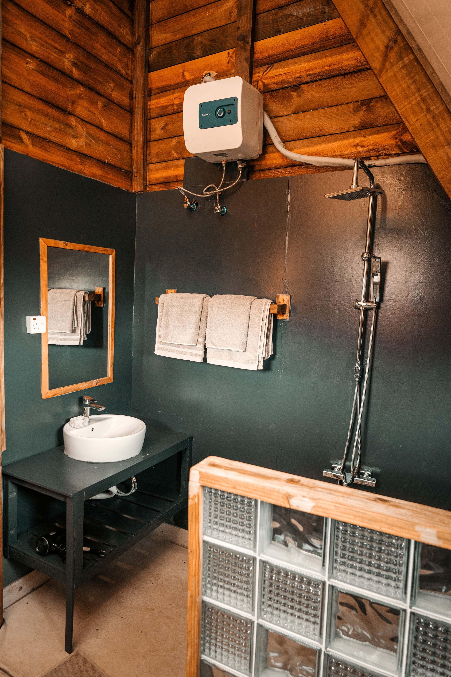 A bathroom with a sink , mirror and towels.
