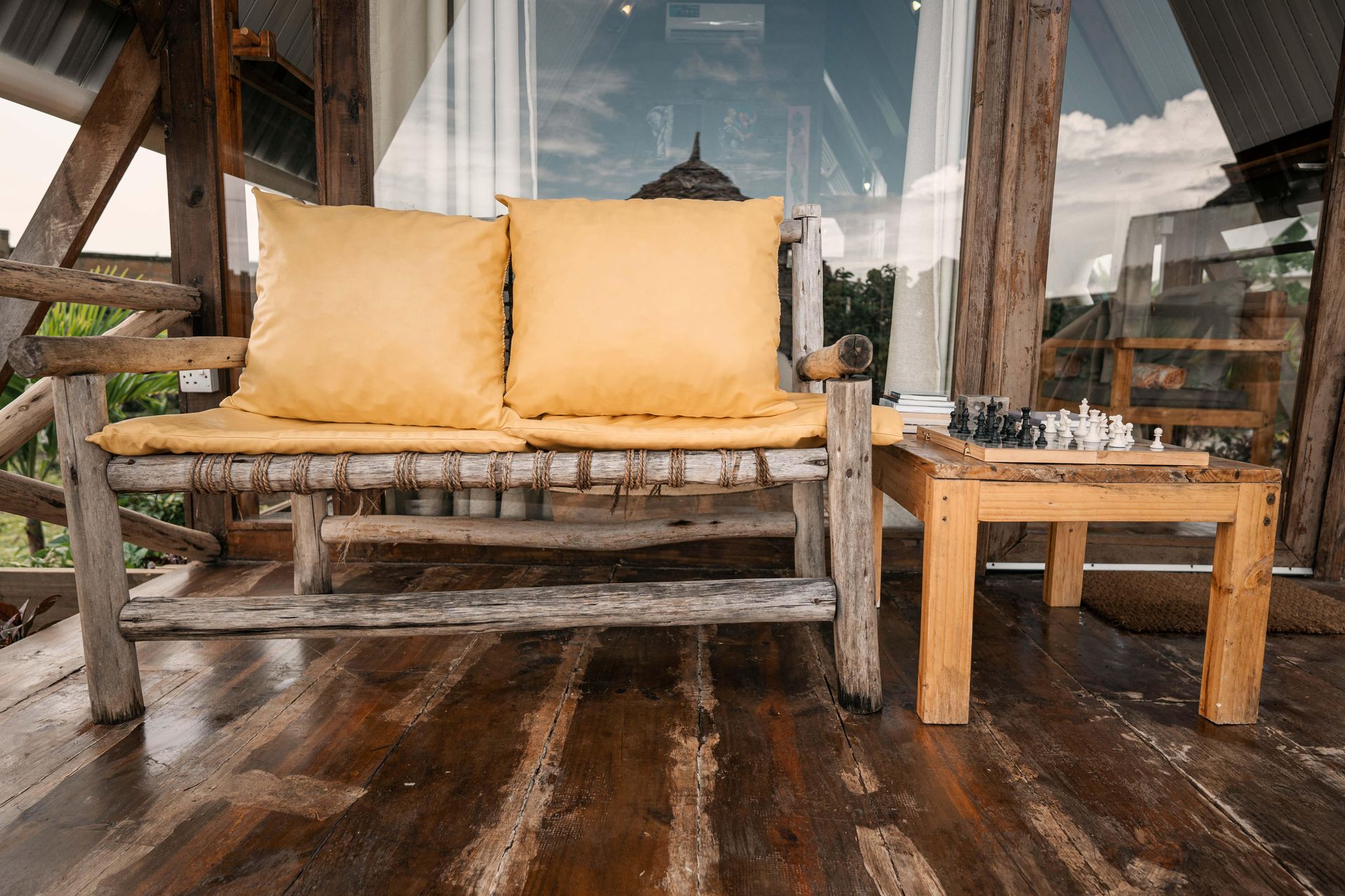 Two wooden chairs with pillows on them are sitting next to each other in front of a window.