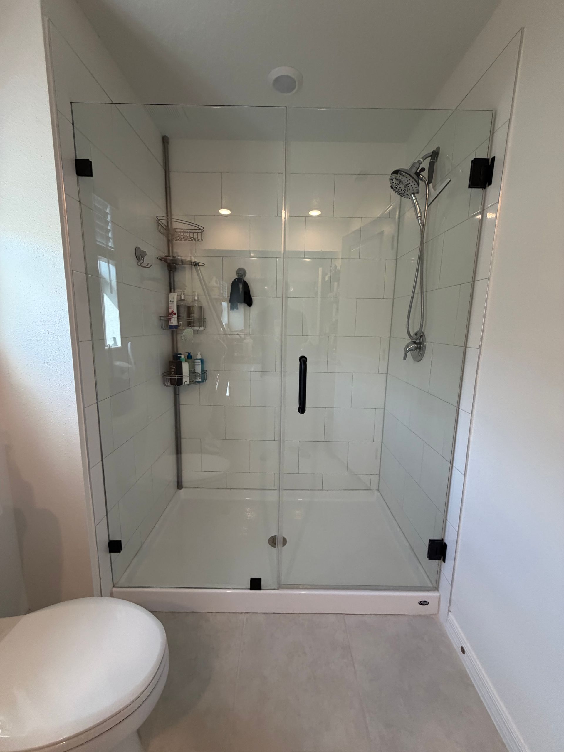 Modern white bathroom with glass walk-in shower and rainfall showerhead.