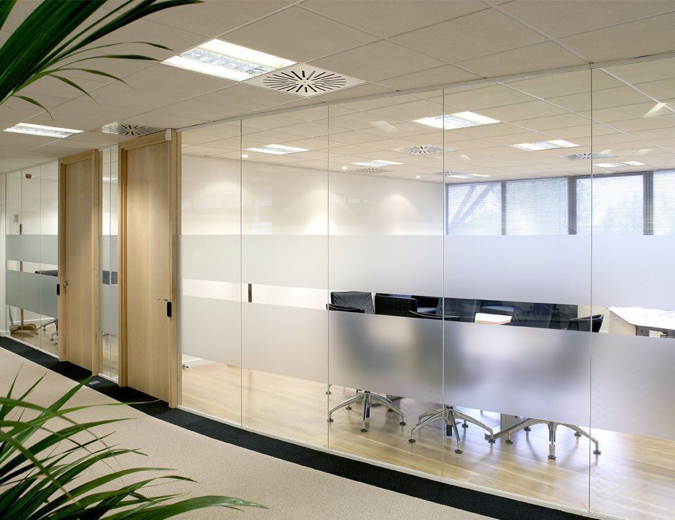 Office glass partition with a frosted privacy band separating a conference room from the open workspace
