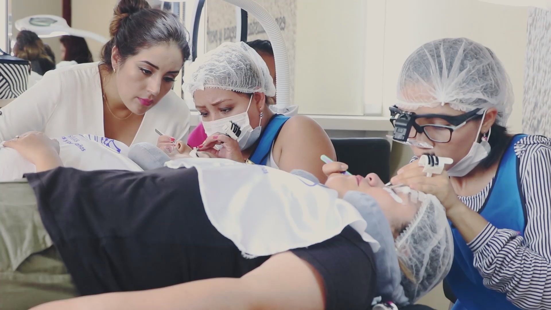 Estudiantes de odontología practicando con un maniquí de paciente en una clínica, con guantes y gorros desechables