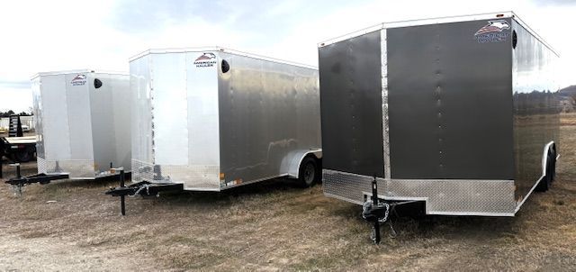 Three trailers are parked next to each other in a field.