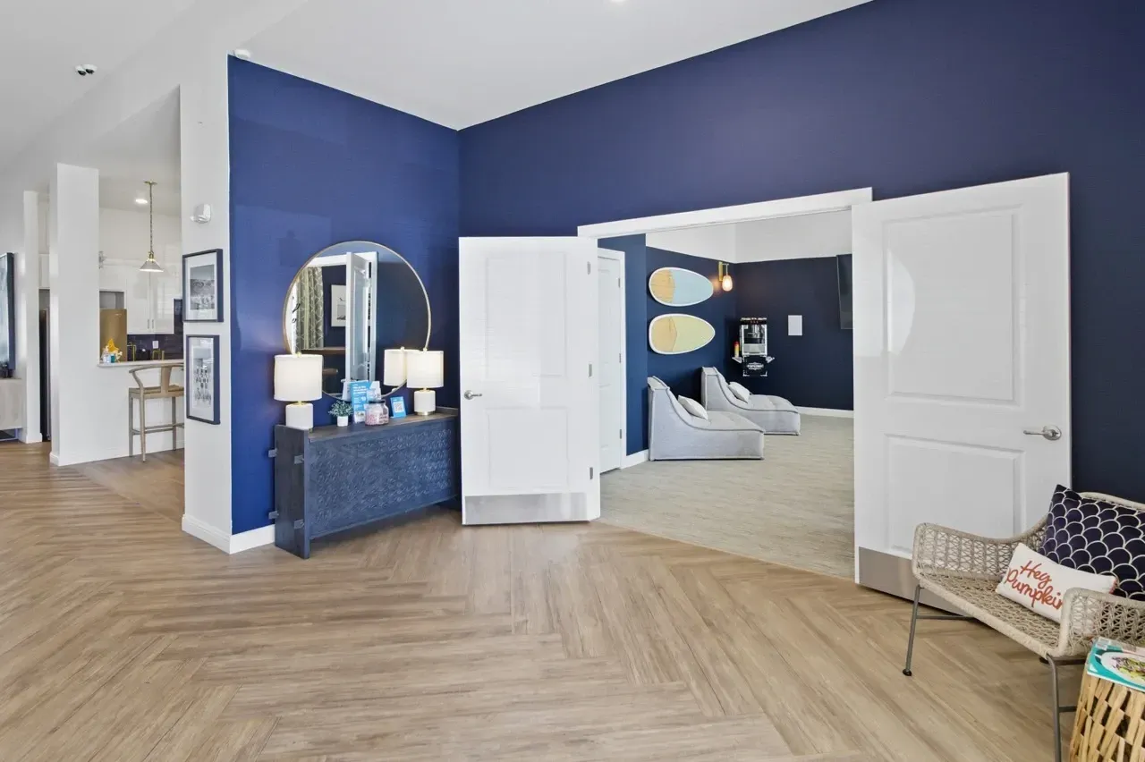 Interior view of a community lounge area with blue walls, surfboard decorations, and lounge chairs.