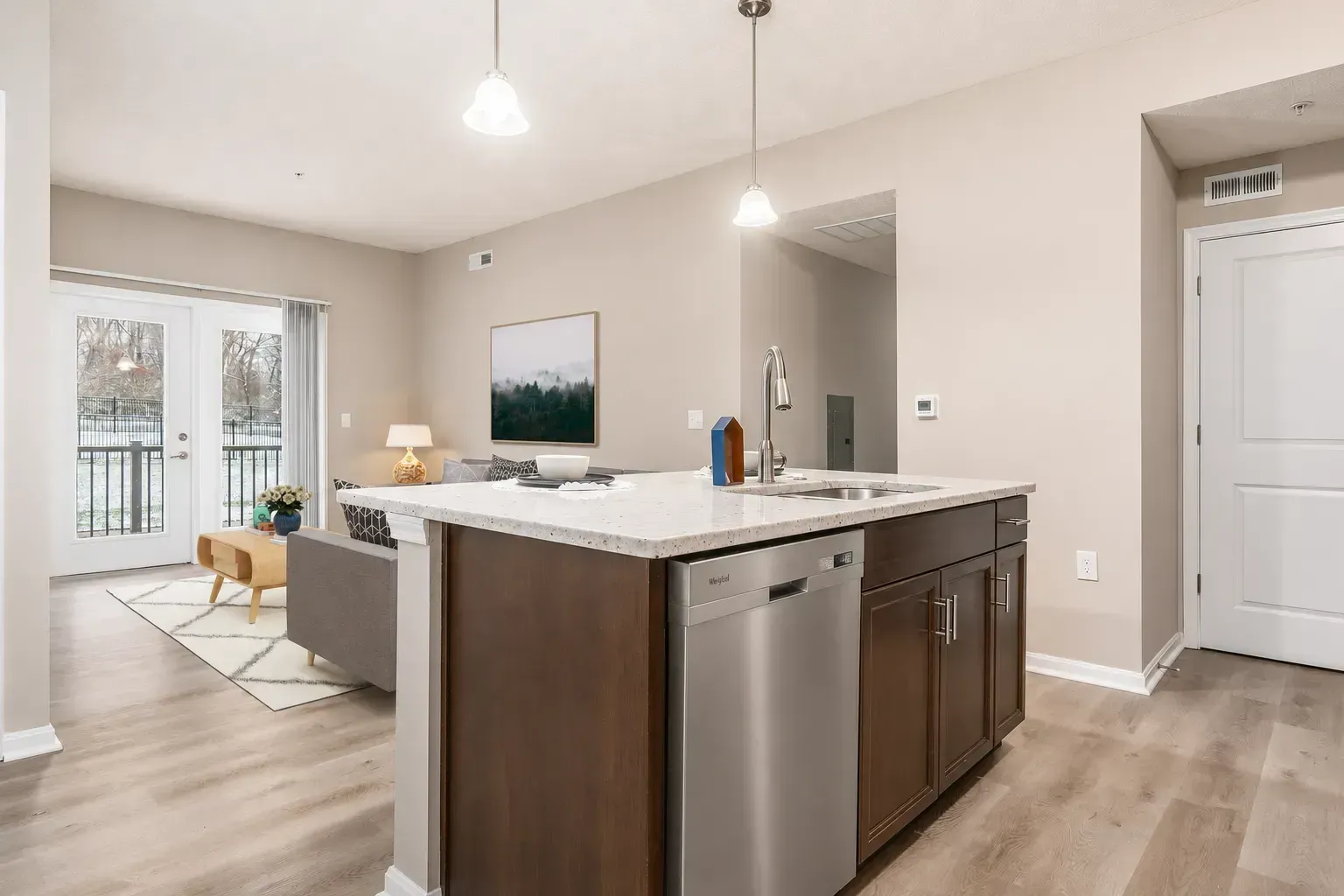 Modern open-concept kitchen and living room with dark cabinets, white island, and light wood floors