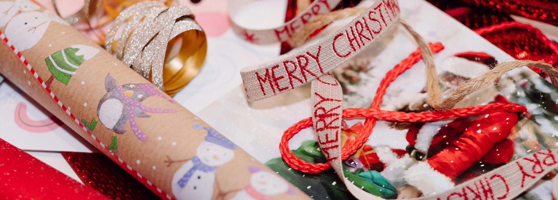 Wrapped Christmas gifts with red ribbons, candy canes, and festive holiday paper on a red surface