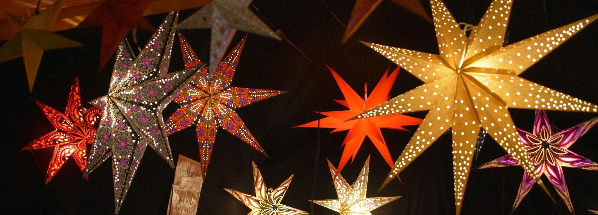 Colorful star-shaped hanging lanterns glowing against a dark background