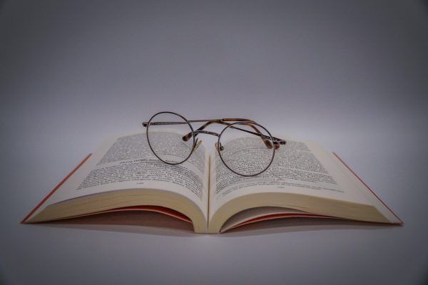Open book with eyeglasses resting on the pages against a gray background