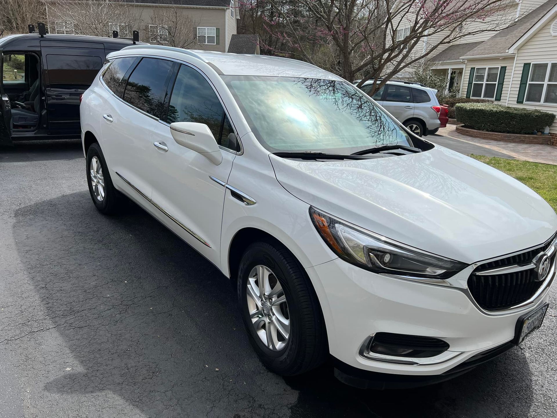 White SUV parked in a driveway outside a suburban house