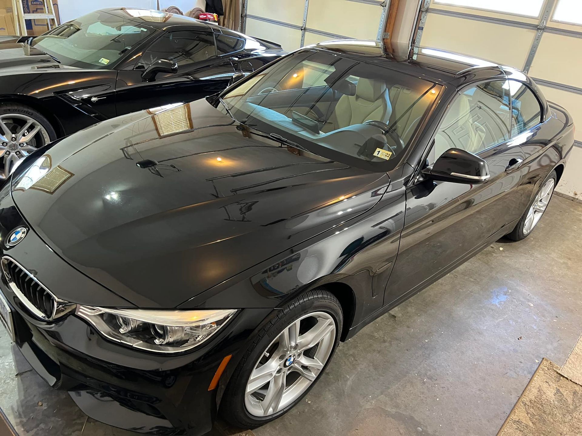 Two black BMW sedans parked indoors in a garage, viewed from above