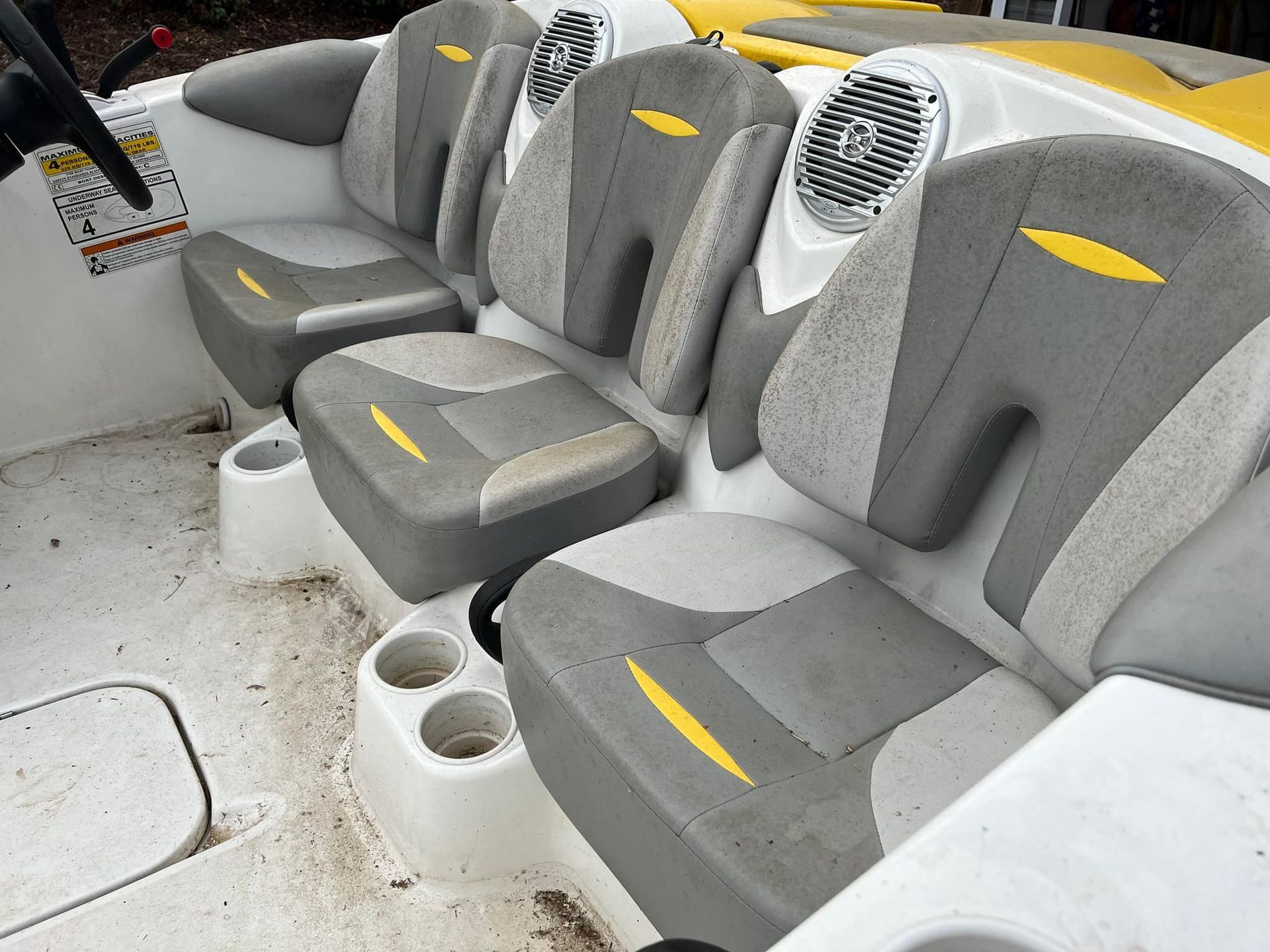 Row of gray-and-white cushioned seats with yellow accents in a boat interior