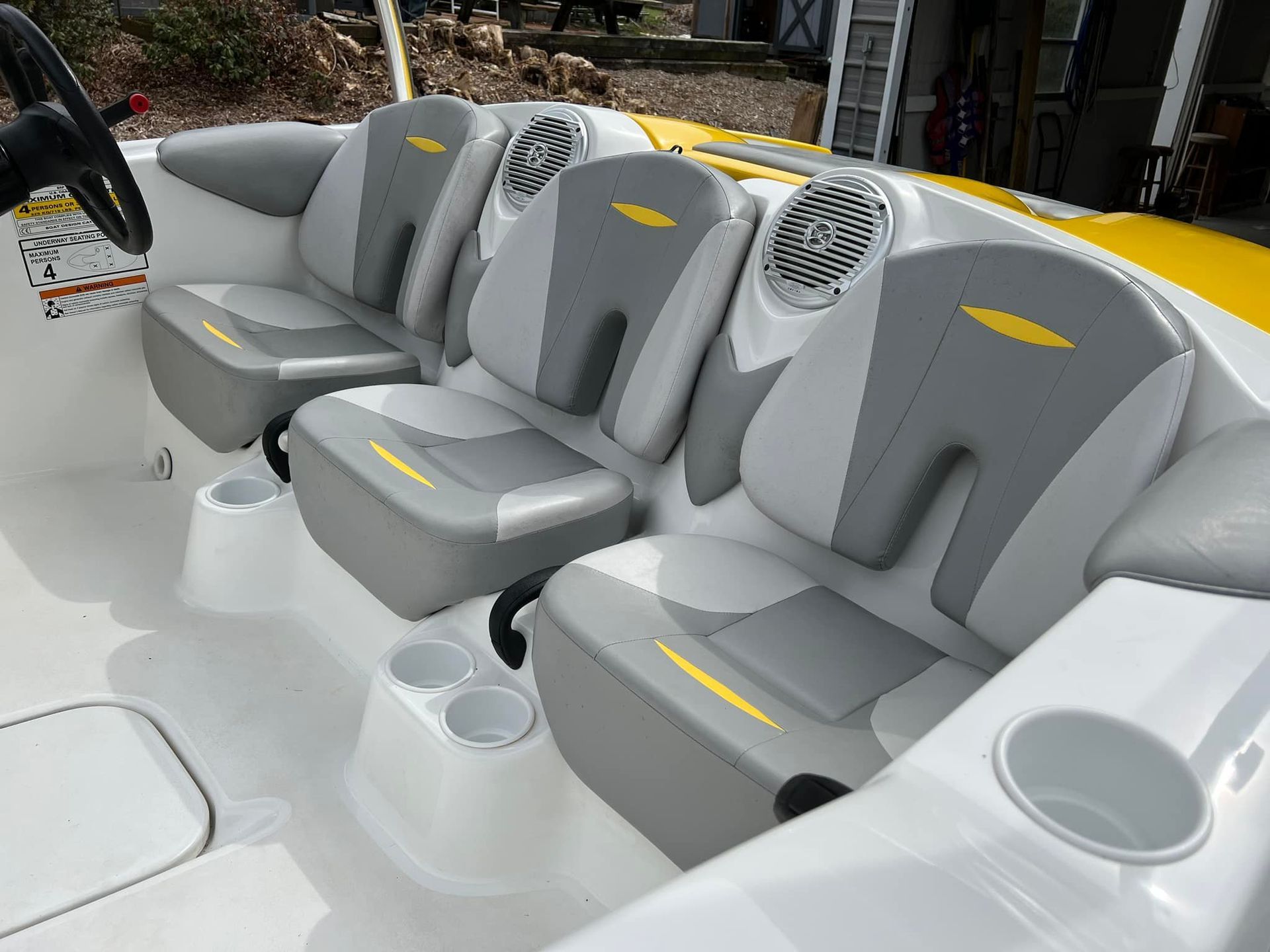 White and gray boat cockpit with three cushioned seats and cup holders, viewed from the stern