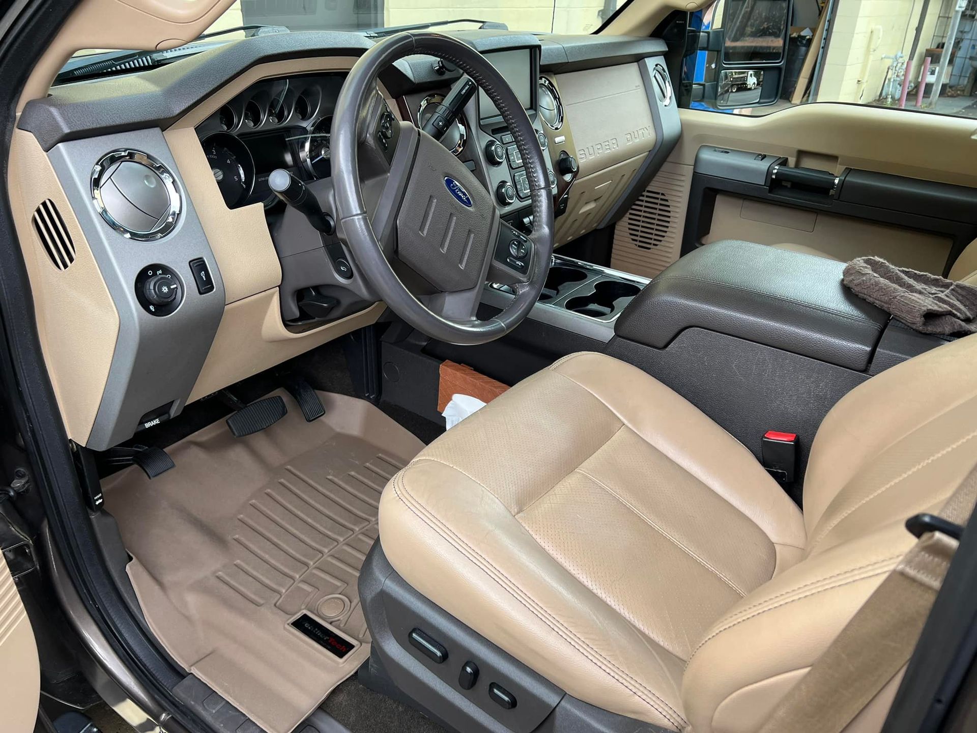 Tan interior of a Ford truck cab with steering wheel, front seats, and center console visible