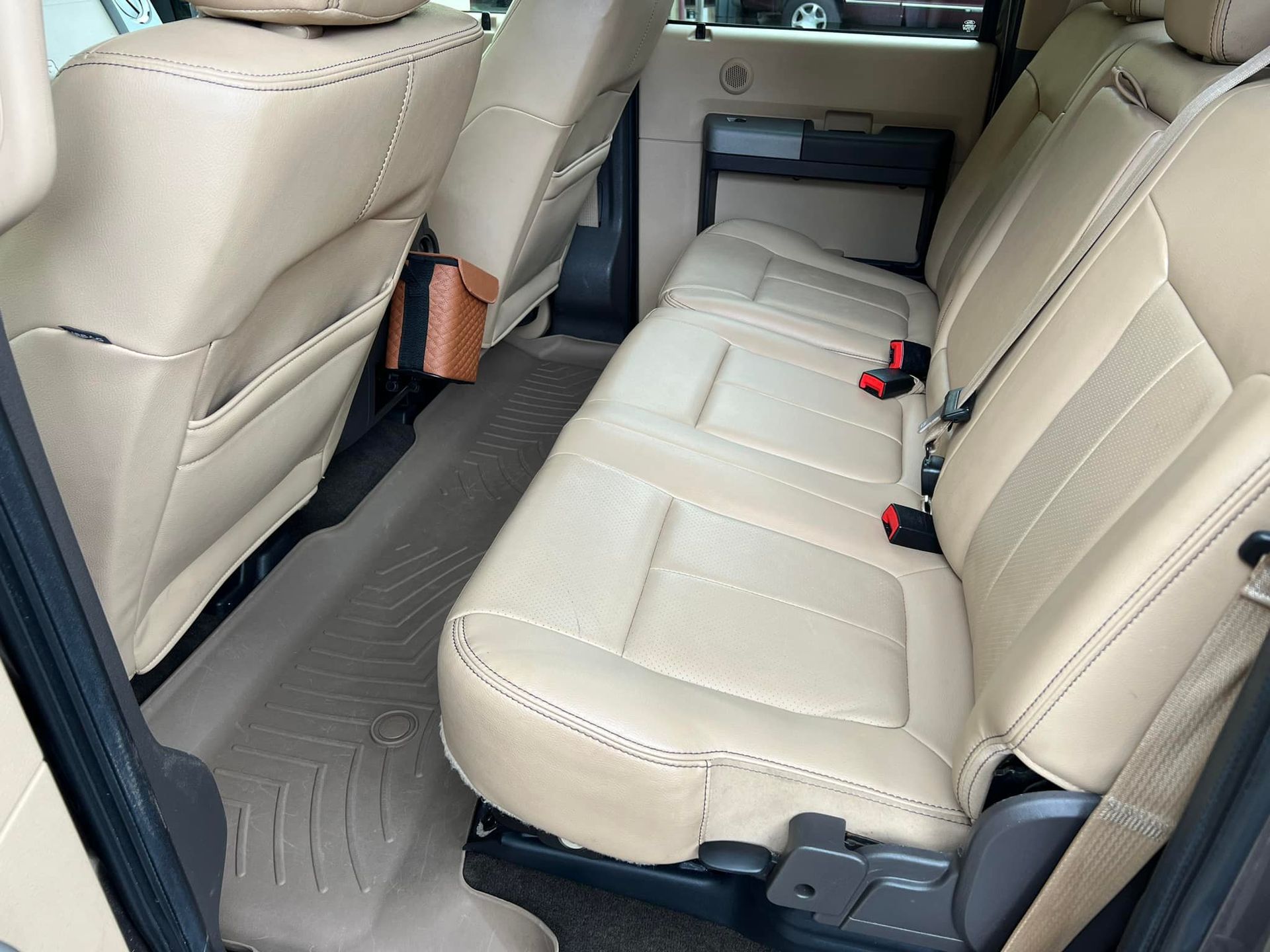 Beige car back seat interior with clean upholstery and seat belts visible