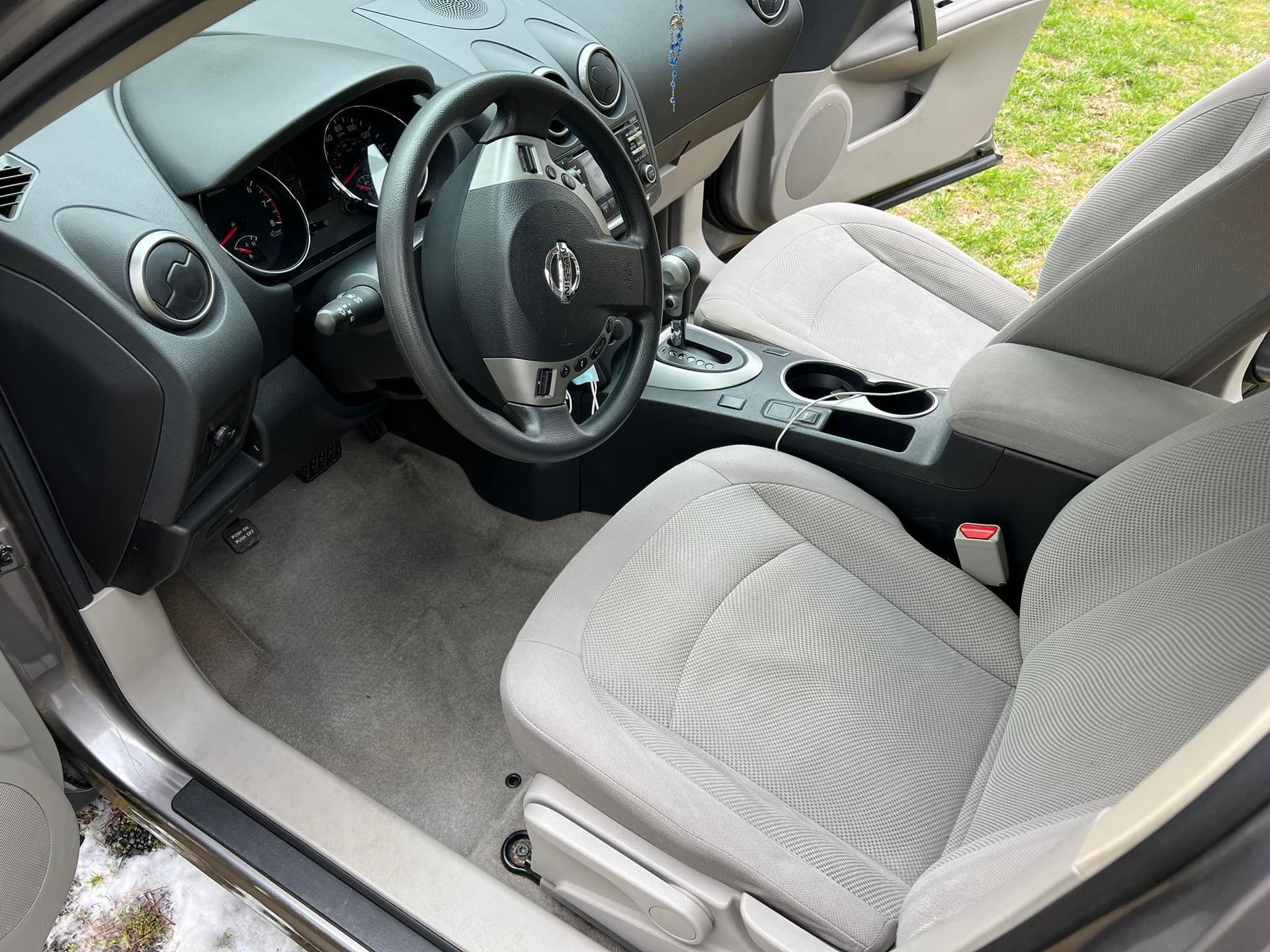 Car interior with gray cloth seats, black dashboard, steering wheel, and center console