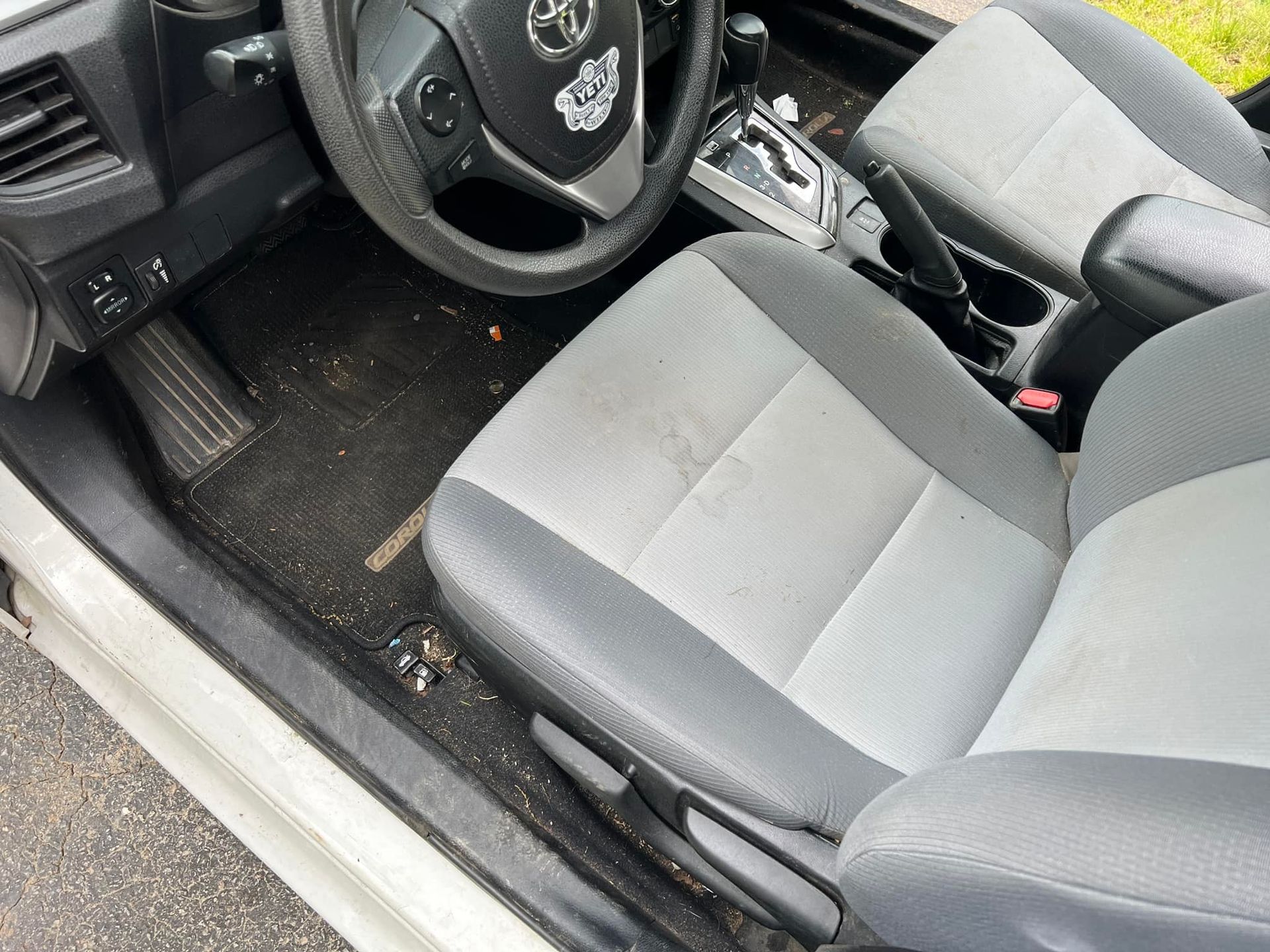 Car interior with gray seats, black floor mats, and steering wheel visible from the driver’s side