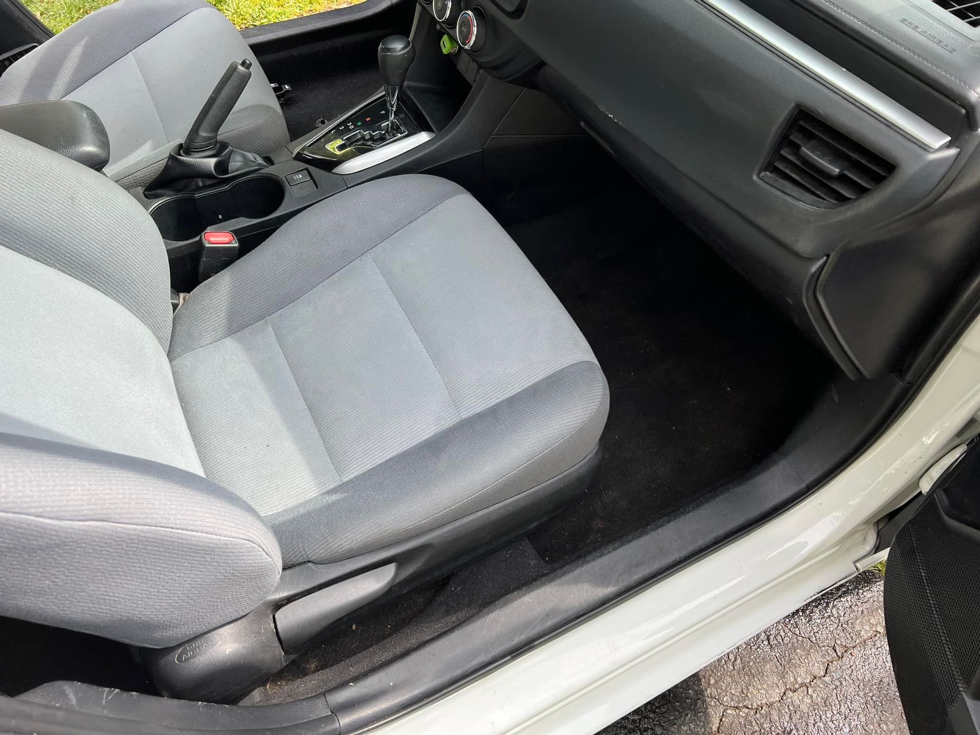 Gray car interior with front passenger seat, dashboard, and center console visible through an open door