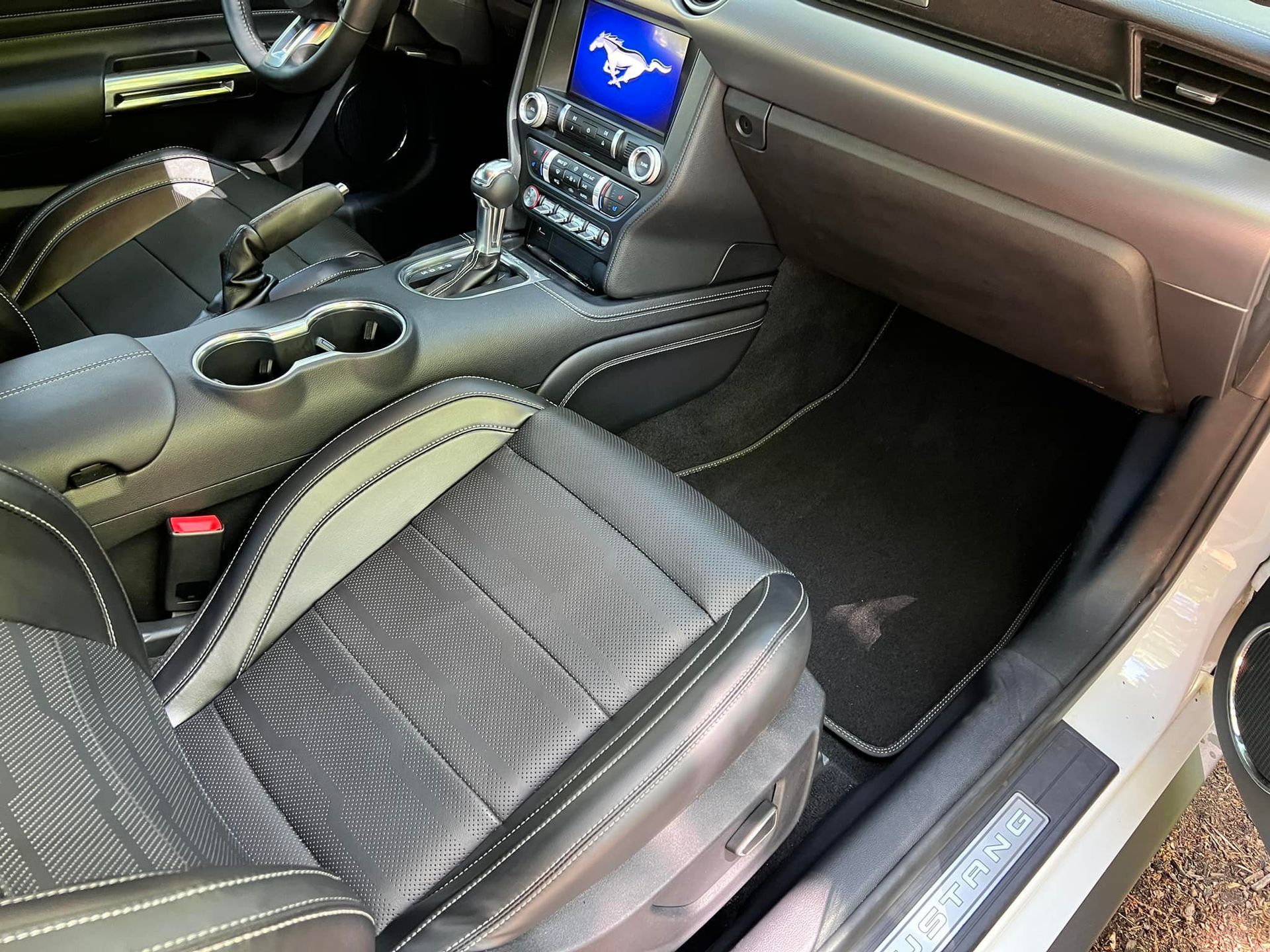 Car interior with black leather seats, center console, and dashboard infotainment screen.