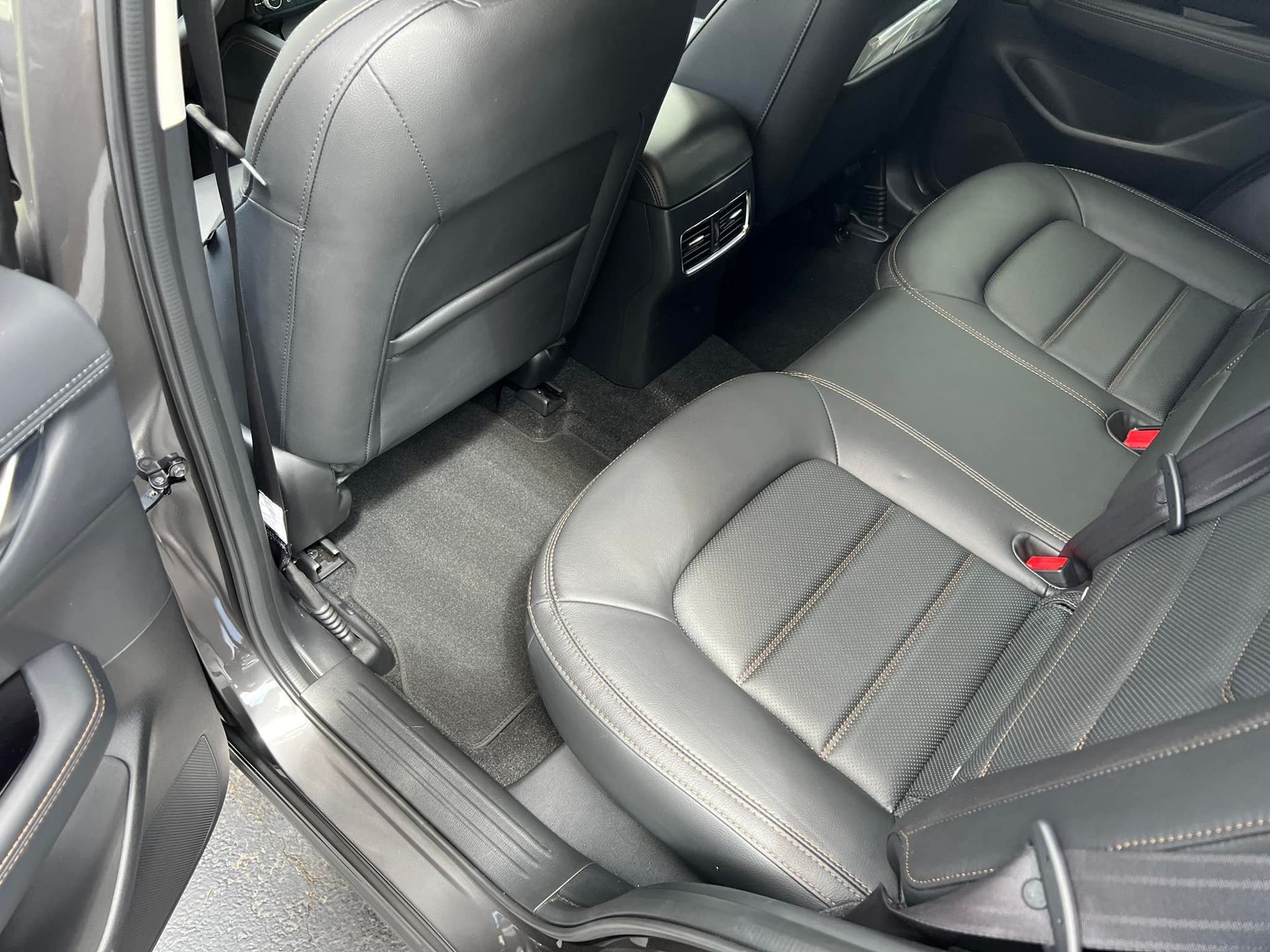 Car interior with black leather rear seats and front seat backs visible.