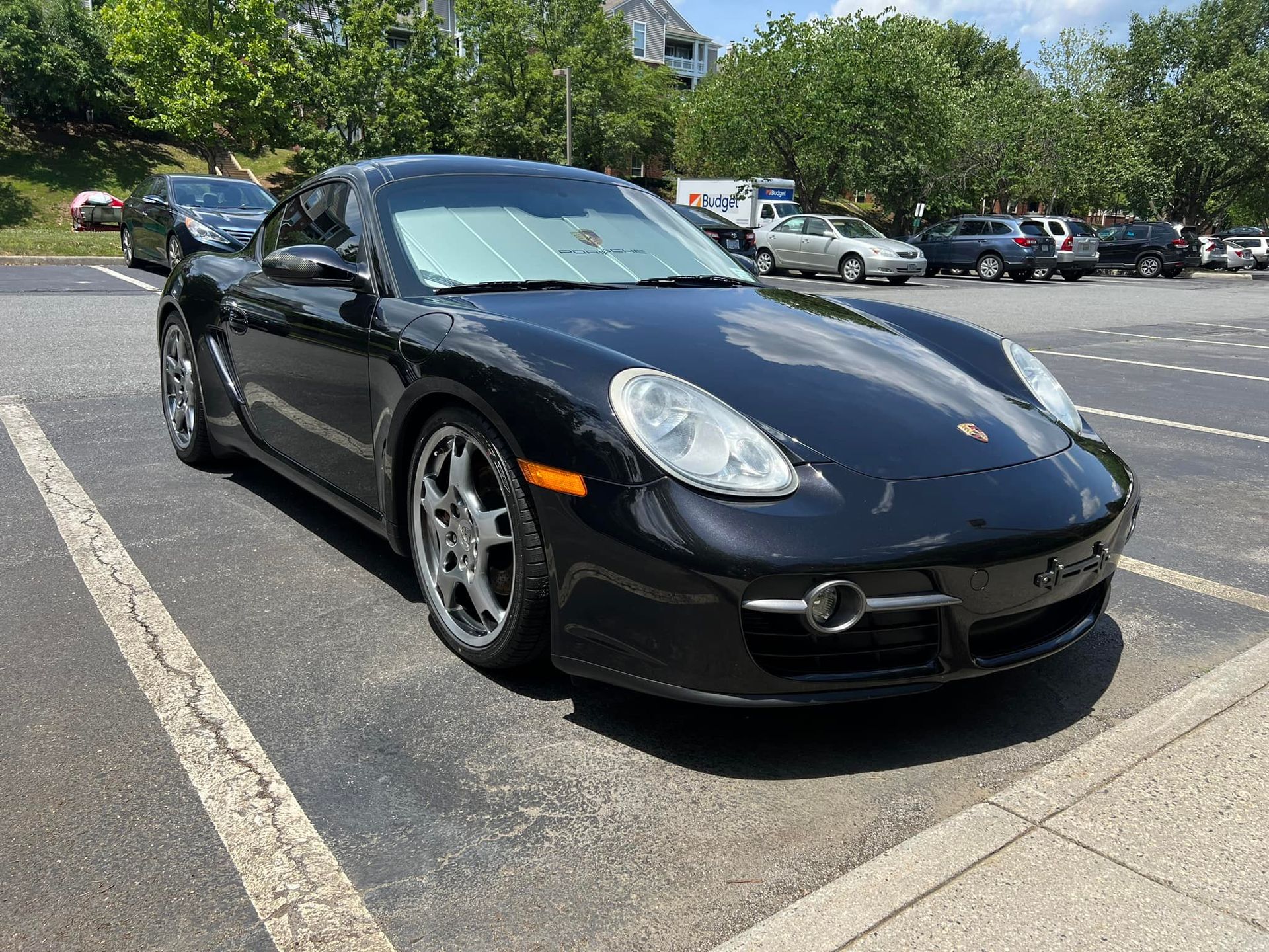 Black Porsche convertible parked in a lot on a sunny day, front-left view