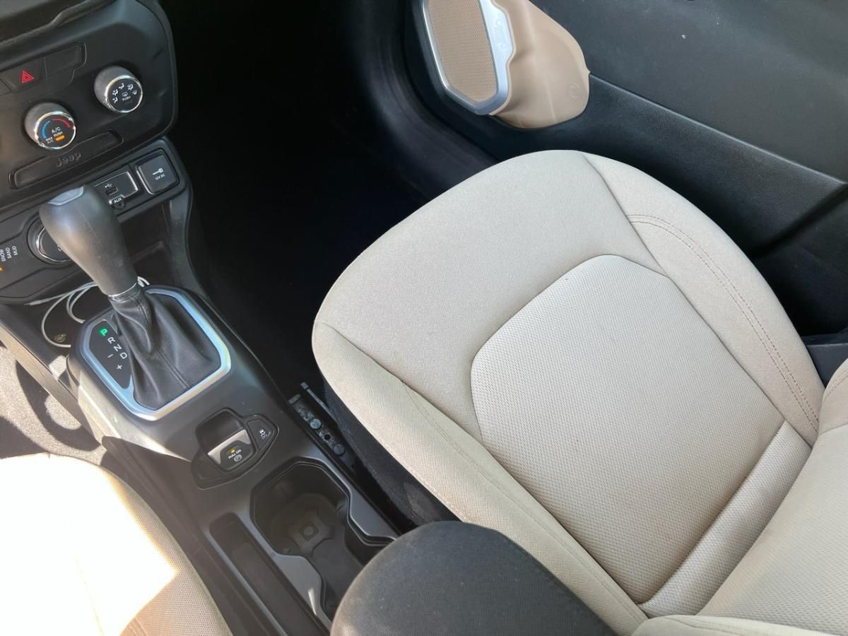 Tan leather car interior with front seats, center console, and black floor mats, viewed from the passenger side