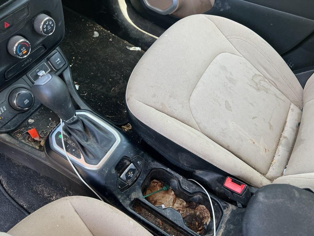 Brown leather car seat and dark interior with center console and floor mat.